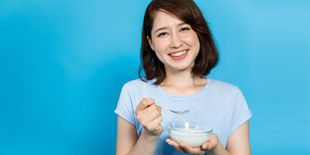 a lady eating yogurt with probiotics for vaginal health