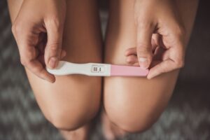 Close-up of a woman holding a positive pregnancy test, reflecting the critical role of progesterone in pregnancy and menstrual health.