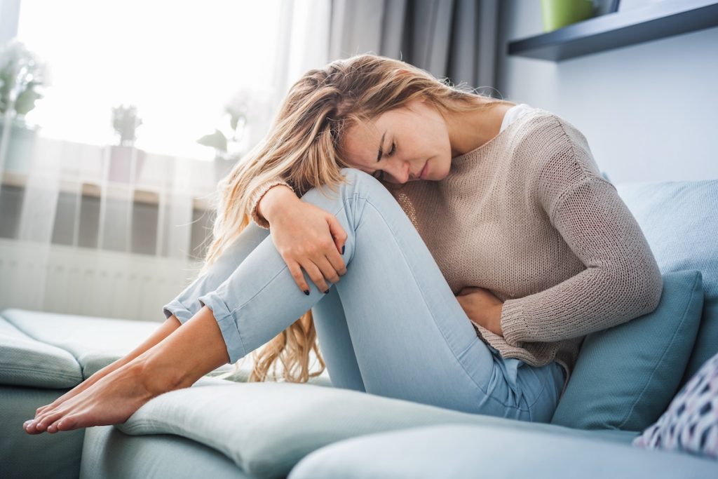 Young woman suffering from strong pain from pelvic organ prolapse