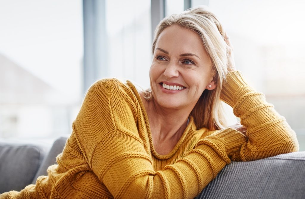 Smiling middle-aged woman relaxed at home, symbolizing relief after TULIP® treatment for lichen sclerosus.
